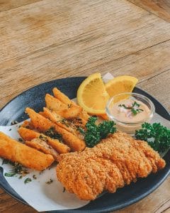 Plate of crispy fried chicken with potato wedges and dipping sauce at The Barn Eatery and Design