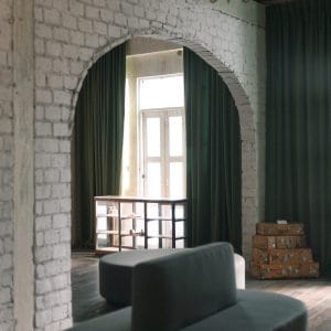 Green-curtained brick archway and tall window in Graph Contemporary's Old City space