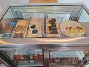 Glass pastry display case of tarts, donuts and cakes at Sukhum Caffe Sanpatong
