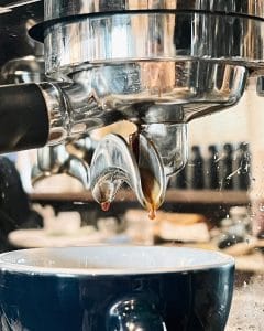Espresso extracting from the machine group head into a cup at The Brewing House by Rue Thai