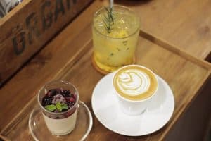 Cappuccino, a berry dessert and a passionfruit drink on a wooden tray at Cafe Arte