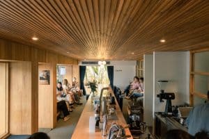 GRAPH quarter's warm timber interior with a long communal counter, wood-slat ceiling and espresso setup