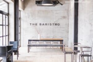The Baristro at Train Station's concrete interior with wall signage and a long communal table