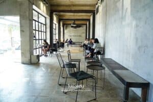 Guests seated at tables along the covered concrete walkway at The Baristro at Train Station