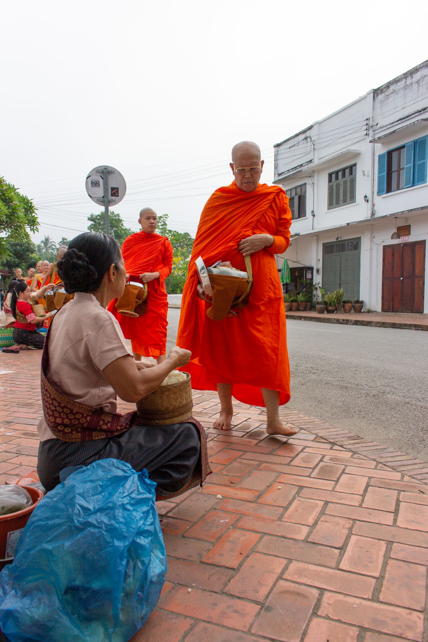 Monks in saffron robes receiving morning alms on a Chiang Mai street