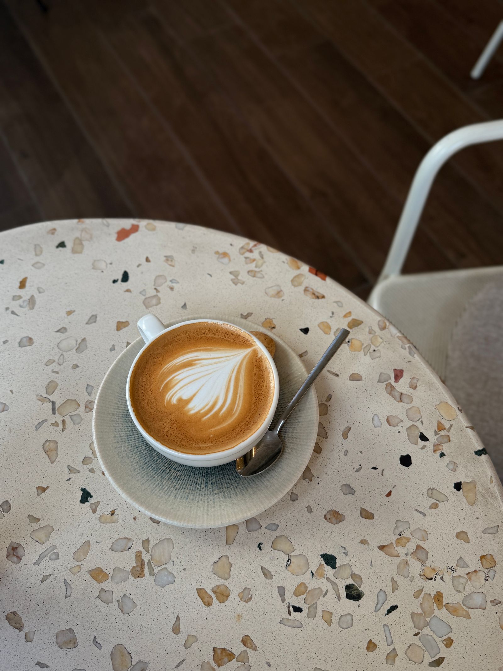 A latte with leaf art on a terrazzo café table