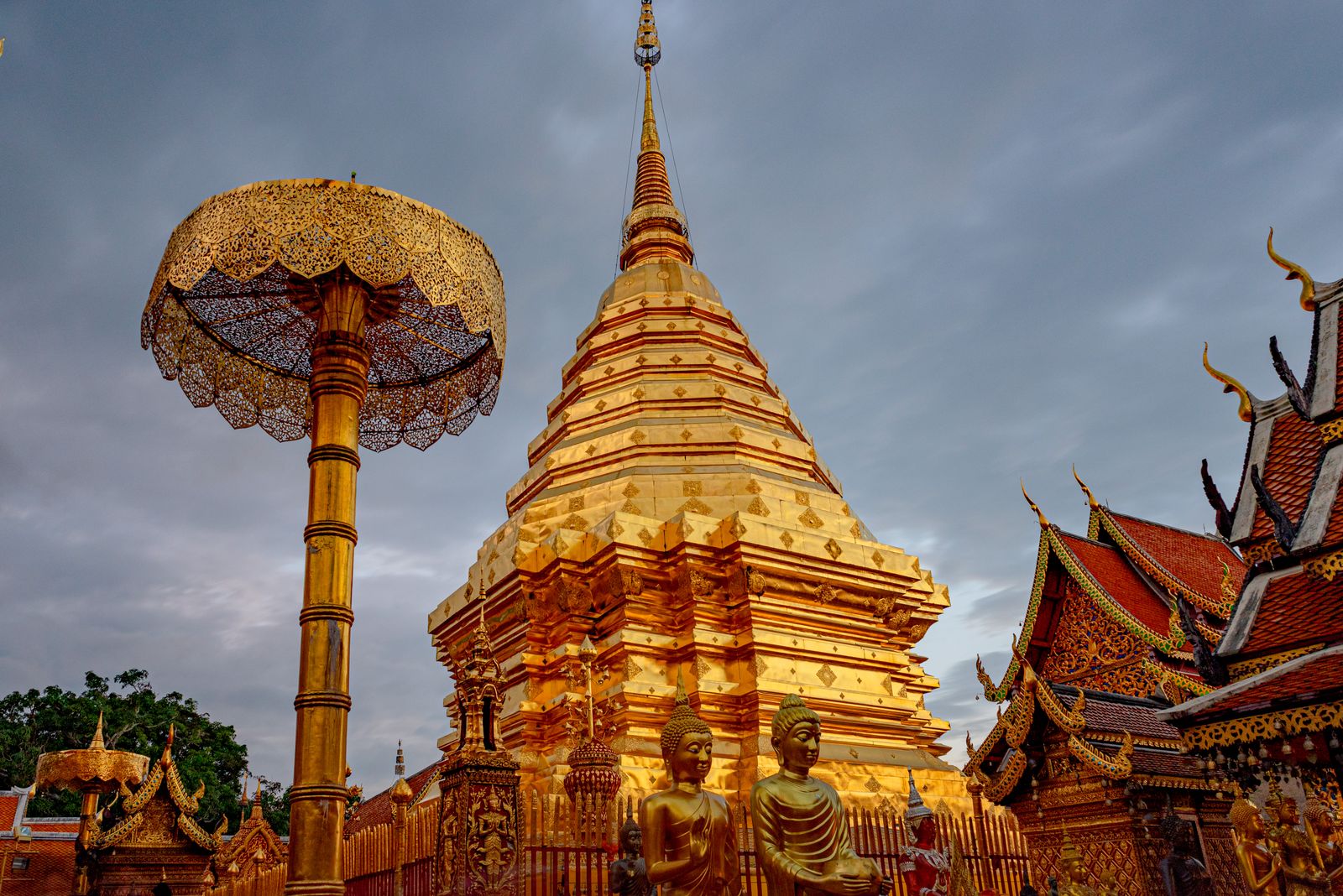 The golden chedi and Lanna umbrella of Wat Phra That Doi Suthep against a moody evening sky