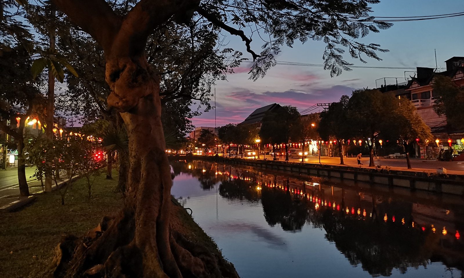 The Chiang Mai old-city moat at dusk, string lights reflected on the water